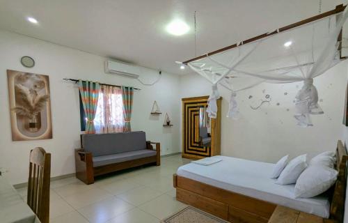 a bedroom with a bed and a couch in it at Villa Tsara Nosy be in Nosy Be