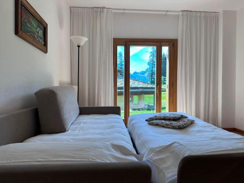 a bed and a chair in a room with a window at Residenza Del Sole in Gressoney-Saint-Jean