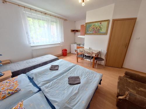 a bedroom with two beds and a table and a kitchen at Modrý dom in Vitanová