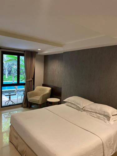 a bedroom with a large white bed and a chair at White Rock Lodge in Nusa Dua