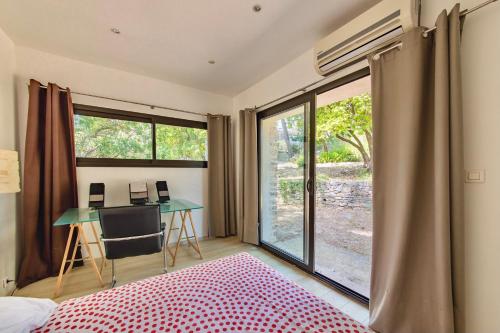 a bedroom with a bed and a desk and a window at villa d'engance et ses dépendances in Nîmes
