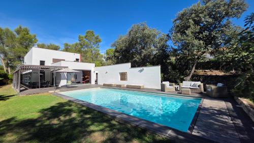 a swimming pool in front of a white house at villa d'engance et ses dépendances in Nîmes