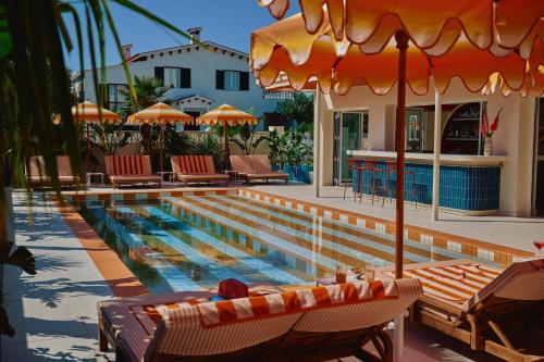 a swimming pool with chairs and umbrellas next to a house at Riviera Hotel Menorca in Ciutadella