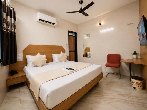a bedroom with a large bed and a red chair at Hotel RR Palace in Rajkot