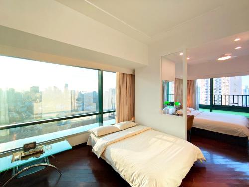 a bedroom with two beds and a large window at Shanghai Cosmo World Union Service Apartment in Shanghai