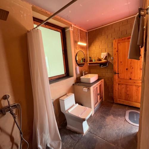a bathroom with a toilet and a sink and a window at Art Mile Kalimpong in Kalimpong