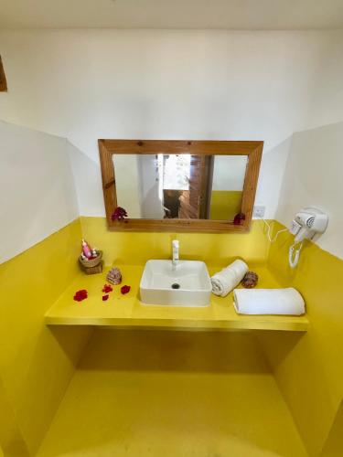 a yellow bathroom with a sink and a mirror at AVO Boutique Hotel in Dikoni