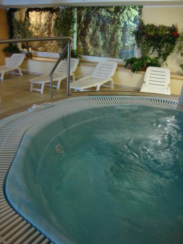 a large swimming pool with white chairs and chairs at Wellness e Resort Stella Delle Alpi in Ronzone
