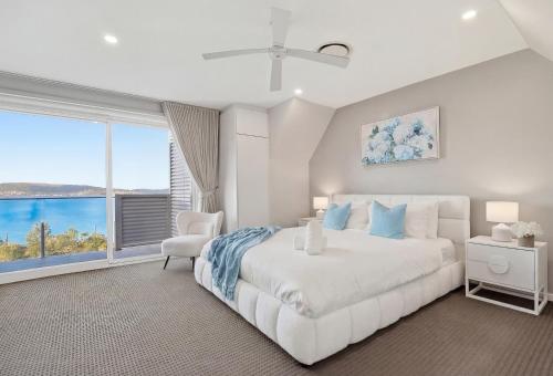 a white bedroom with a large bed and a window at Bayview Luxe Retreat in Tascott