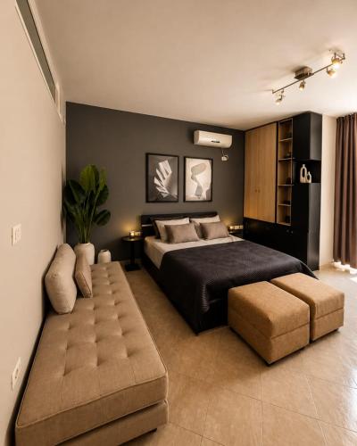 a bedroom with a large bed and a ottoman at Hotel Kamomil in Durrës