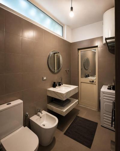 a bathroom with a sink and a toilet and a mirror at Hotel Kamomil in Durrës