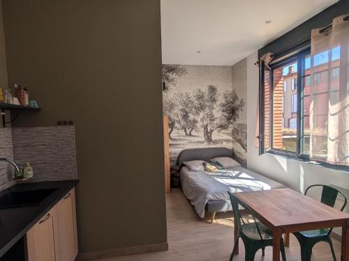 a kitchen with a table and a bed in a room at Moustier in Montauban