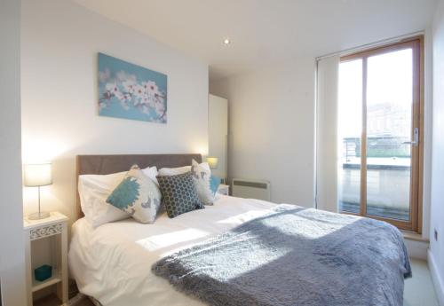 a bedroom with a large white bed with a window at By The Bridge Apartments in Inverness