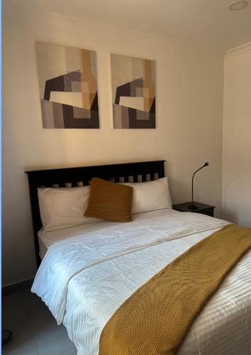 a bed in a bedroom with three paintings on the wall at JAYNIEL Apartments in Lusaka