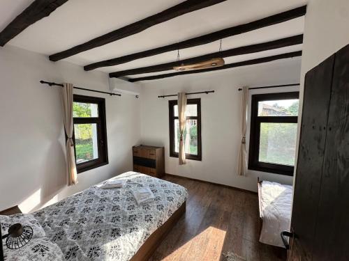 a bedroom with a bed and two windows at Bachvarov house Бъчваровата къща in Palitsi