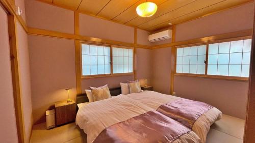 a bedroom with a large bed with two windows at Tabinoteitaku 和-WA- in Sendai