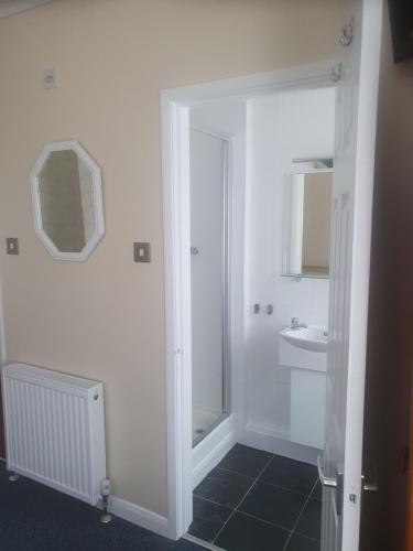 a white bathroom with a shower and a sink at Smugglers Rest in Newquay