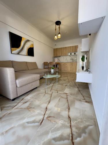 a living room with a couch and a table on a marble floor at Coral Blue By Infinity in Nea Kallikrateia