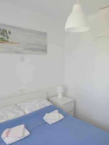 a white bedroom with a blue bed and a painting at Apartments Zlata in Lopar