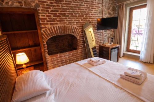 a bedroom with a white bed with a brick fireplace at Blue Boz Küçükköy in Ayvalık