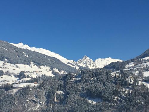 a view of a snowy mountain with trees and mountains at Ferienwohnung Gruber-Hansen in Kaltenbach