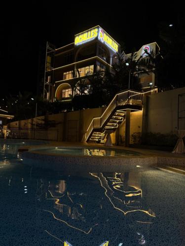 a resort with a swimming pool at night at Achilles Hotel in Maitim