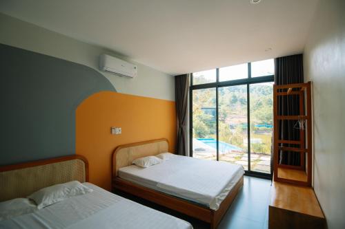 two beds in a room with a window at Daisy Queen Village Ba Vì in Yên Cư