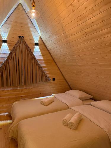 two beds in a room with a wooden ceiling at Tera Cottages kazbegi in Kazbegi
