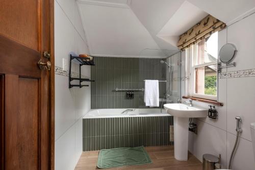 a bathroom with a bath tub and a sink at Glen Eden Lodge in Lidgetton