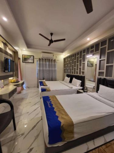 a hotel room with two beds and a ceiling fan at Hotel Shreesh Mayapur in mayapur