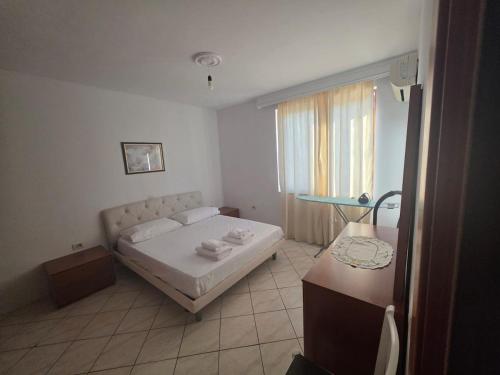 a bedroom with a bed and a table and a window at Comfort Saranda Apartment in Sarandë