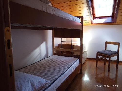 a bedroom with two bunk beds and a chair at Casa Bezzi in Pellizzano