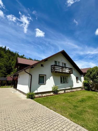 a white house with a balcony on the side of it at Casa Popa’s in Cârțișoara