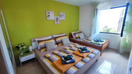 a bedroom with two beds and a green wall at Apartmani Anastazija in Karlobag