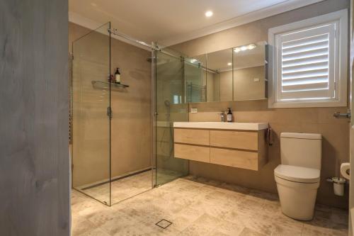 a bathroom with a shower and a toilet and a sink at Handleys Cottage in High Range