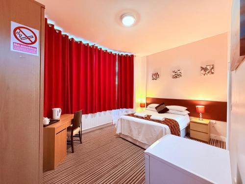 a hotel room with a bed and a red curtain at RBS Hotel, Rochester in Rochester