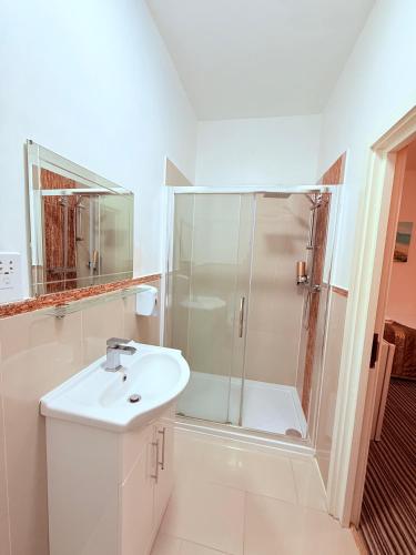 a white bathroom with a shower and a sink at RBS Hotel, Rochester in Rochester