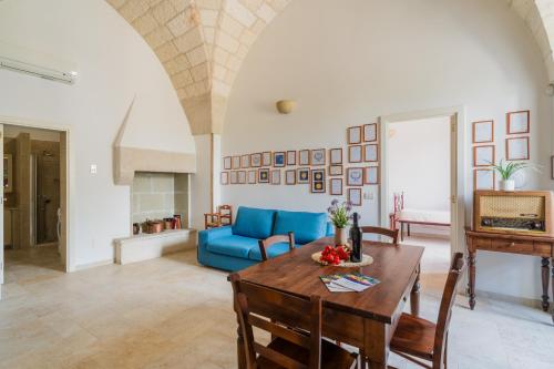 a living room with a table and a blue couch at Tre Volte Belle - Salento Selection in Carpignano Salentino