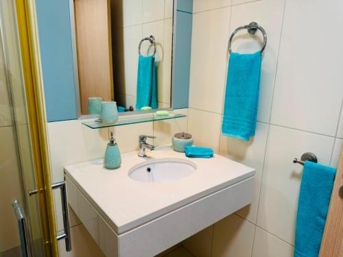 a bathroom with a sink and a mirror and blue towels at Santa Maria Ilha do Sal T2 Apartament with pool A&L em Vila Verde in Prainha