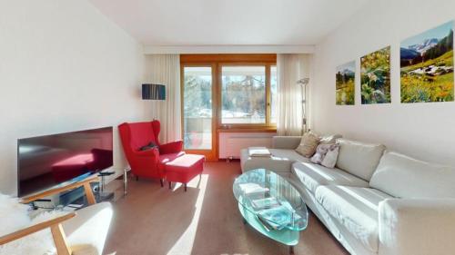 a living room with a white couch and red chairs at Residenz Alpina im Kurhaus in Lenzerheide