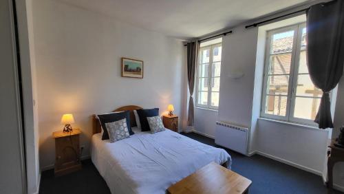 ein Schlafzimmer mit einem Bett und zwei Fenstern in der Unterkunft Le Sed' in Nérac