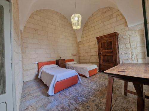 a room with two beds and a table in it at Dimora Pietra E Luce By Cala Salento in Vignacastrisi