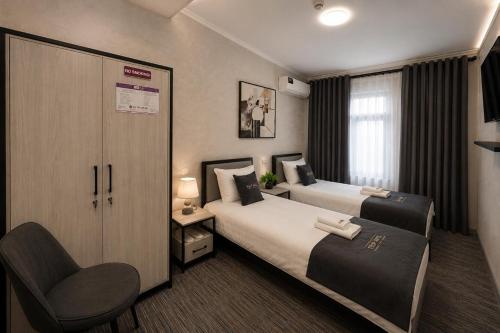 a hotel room with two beds and a chair at TRIP Hotel in Toshkent-Passajir Bekati