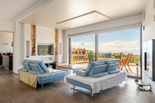 a living room with blue furniture and a large window at White Sand Loutraki Villa - Sea View in Loutraki