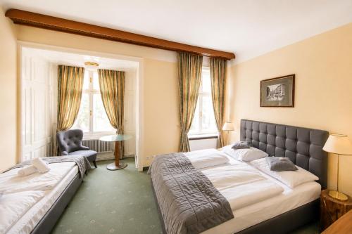 a bedroom with two beds and a table and windows at Hotel Bergwirt Schönbrunn in Vienna