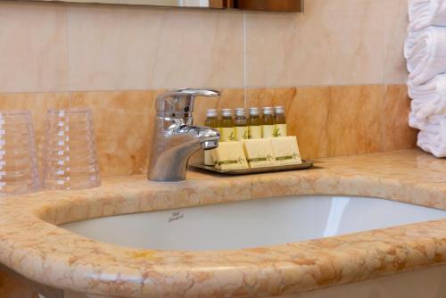 a bathroom sink with a faucet and bottles of oils at Parc Hotel Casa Mia in Lazise