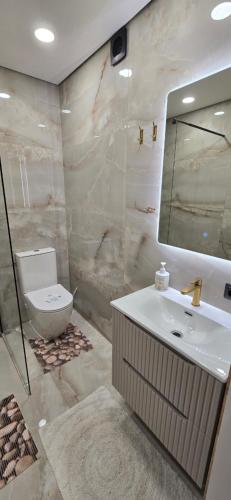 a bathroom with a sink and a toilet and a mirror at Apartamentai šalia baseino in Palanga