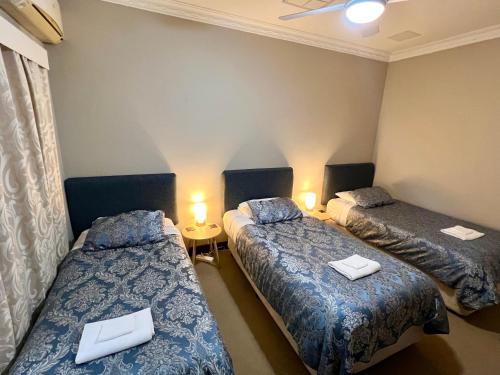 a room with two beds and a table with lamps at Bõucher Manor - Northam in Northam