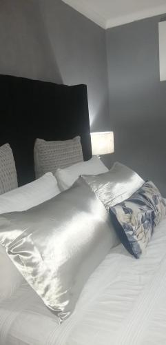 a bed with white sheets and a lamp on it at Radiant Residence in Grahamstown
