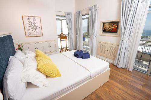 a bedroom with a large white bed with yellow pillows at Me & U - הווילה שלי בכנרת in Tel Kazir